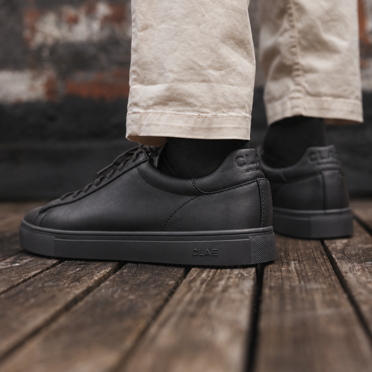CLAE Bradley Essentials Triple Black Leather with black socks — side view lifestyle